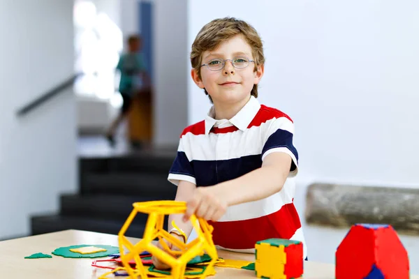 Happy kid jongen met bril veel plezier met het bouwen en maken van geometrische figuren, leren wiskunde en meetkunde — Stockfoto