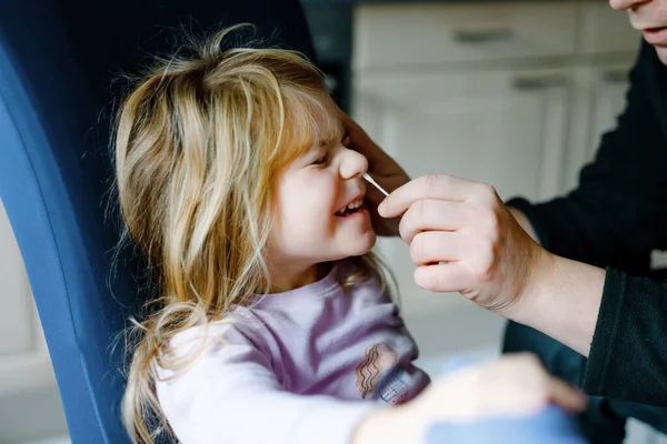 Father making nasal home corona virus tast to little girl, preschool child. Daughter and dad take covid home antigen test with cotton swab. — Stock Photo, Image