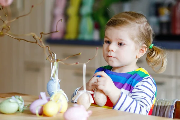 Nettes kleines Mädchen, das Baumzweige mit farbigen pastellfarbenen Plastikeiern dekoriert. Glückliches Baby, das Spaß an der Osterdekoration hat. Liebenswert gesundes lächelndes Kind im Familienurlaub — Stockfoto