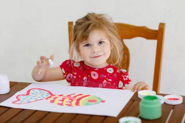 Pequena criança criativa pintura menina com cores de dedo um peixe. Criança ativa se divertindo com desenho em casa, no pré-escolar ou pré-escolar. Educação e educação à distância para crianças. Actividade cremosa. — Fotografia de Stock