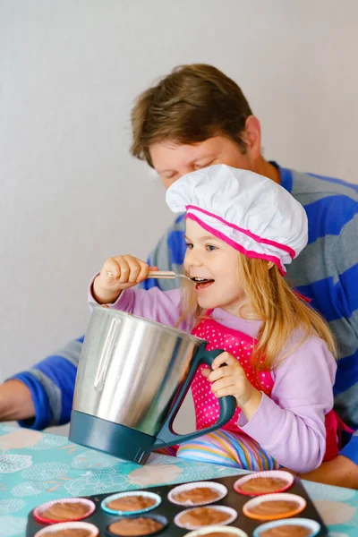 Şirin küçük kız ve baba evde ev yapımı çikolatalı kek pişiriyorlar. Mutlu anaokulu çocuğu ve babası birlikte ev mutfağında. — Stok fotoğraf