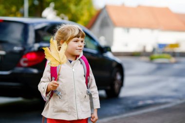Okuldaki ilk gününde tatlı küçük bir anaokulu kızı. Sağlıklı, mutlu bir çocuk anaokuluna gidiyor. Sırt çantalı çocuk şehir sokaklarında kreşe gidiyor.