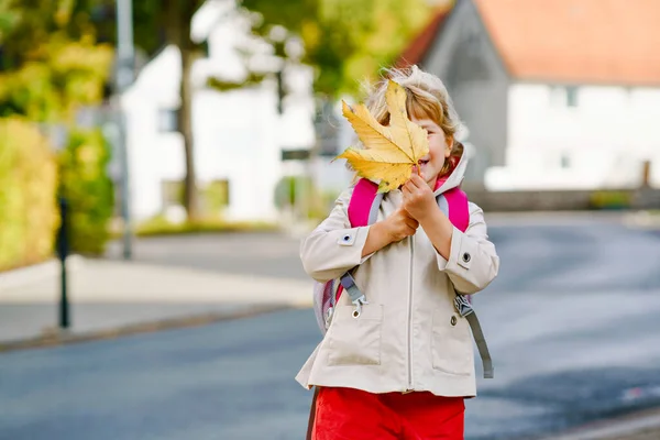 Χαριτωμένο κοριτσάκι προσχολικής ηλικίας την πρώτη μέρα που πήγε σχολείο. Υγιές χαρούμενο παιδί που πηγαίνει στο νηπιαγωγείο. Παιδί με σακίδιο πηγαίνει στον παιδικό σταθμό στο δρόμο της πόλης, σε εξωτερικούς χώρους — Φωτογραφία Αρχείου