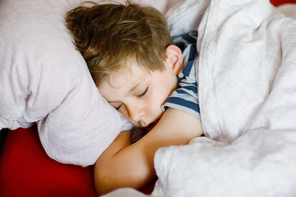 En ung pojke sover i sängen. Skolbarn drömmer. Trött tonårssömn. — Stockfoto