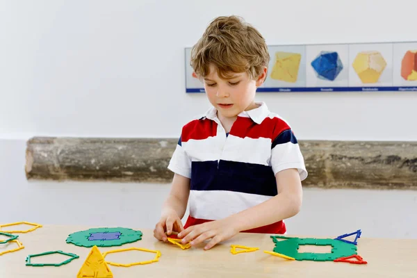 Счастливый мальчик весело строит и создает геометрические фигуры, изучает математику и геометрию — стоковое фото