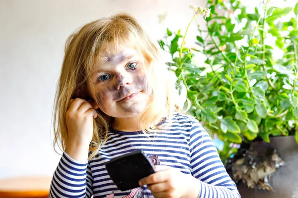 Vtipné malé batolátko, které používá matčiny make-up a maluje obličej očními stíny. Šťastné dítě dělá experimenty s kosmetikou matky. Kid around — Stock fotografie