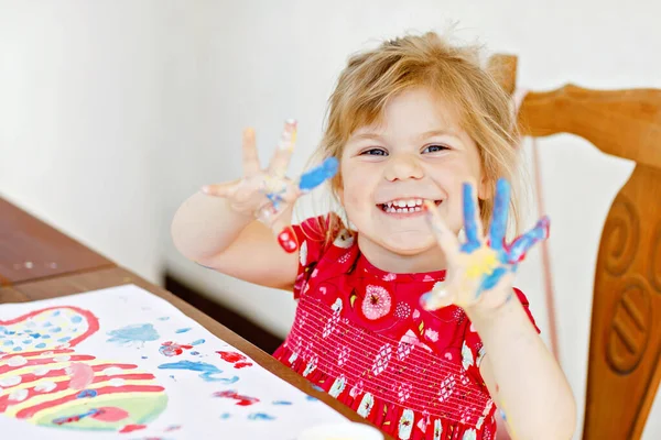 Little creative toddler girl painting with finger colors a fish. Active child having fun with drawing at home, in kindergaten or preschool. Education and distance learning for kids. Creaitve activity. — Stock Photo, Image