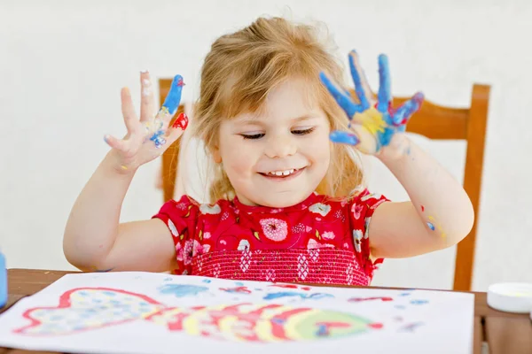 Little creative toddler girl painting with finger colors a fish. Active child having fun with drawing at home, in kindergaten or preschool. Education and distance learning for kids. Creaitve activity. — Stock Photo, Image