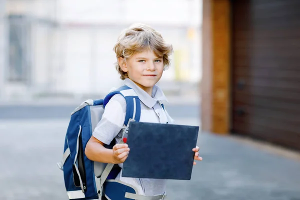 Gelukkige kleine jongen met rugzak of tas genaamd Ranzen in het Duits. Schoolkind op weg naar school. Gezond schattig kind buiten Op de balie Eerste dag tweede klas in het Duits. Terug naar school. — Stockfoto