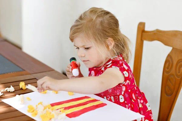 Lite kreativ småbarn flicka målning med finger färger popcorn box och göra pappersliktornar med lim. Aktivt barn har kul med att rita gör hantverk. Utbildning för barn. Kreaitveverksamhet. — Stockfoto