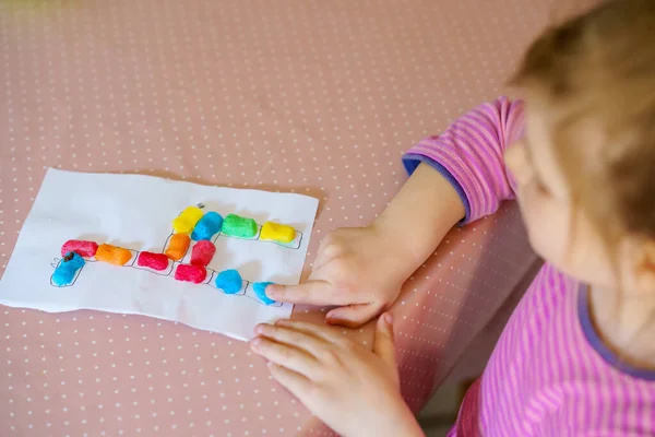 Küçük yaratıcı kız, oyuncaklarla renkli zürafalar yapıyor. Aktif mutlu çocuk çizim yaparken eğleniyor. Çocuklar için eğitim. Komik aktivite. — Stok fotoğraf