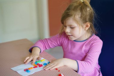 Küçük yaratıcı kız, oyuncaklarla renkli zürafalar yapıyor. Aktif mutlu çocuk çizim yaparken eğleniyor. Çocuklar için eğitim. Komik aktivite.