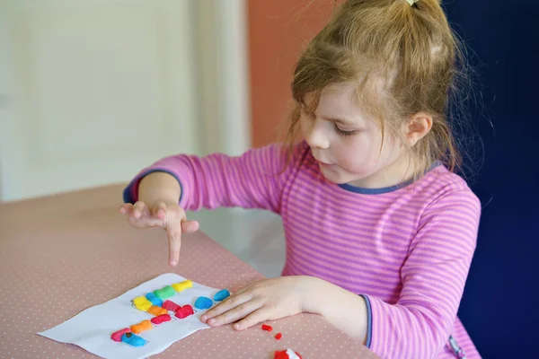 Egy kis kreatív kislány színes zsiráfot csinál playmaikkal. Aktív boldog gyermek szórakozás rajz csinál kézműves. Oktatás gyerekeknek. Vicces tevékenység.. — Stock Fotó