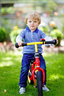 Aktif sarışın çocuk renkli giysiler içinde denge kuruyor ve bisikleti ya da bisikleti yurtiçinde öğreniyor. Küçük çocuk sıcak yaz gününde rüya görüyor ve eğleniyor. Çocuklar için açık hava hareket oyunu