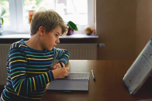 Niño de la escuela que trabaja duro haciendo tarea durante el tiempo de cuarentena de la enfermedad pandémica corona. Niño en casa escolarización en coronavirus tiempo covid, escuelas cerradas. Concepto de educación en el hogar —  Fotos de Stock