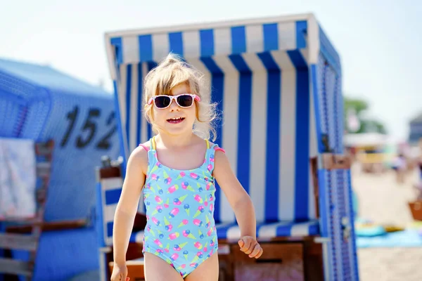 Kleine Vorschulmädchen spielen mit Sandspielzeug am Strand. Nettes glückliches Kleinkind im Familienurlaub am Meer. Kind in der Nähe überdachter Strandkörbe an der Ostsee. Aktivitäten im Freien für Kinder — Stockfoto