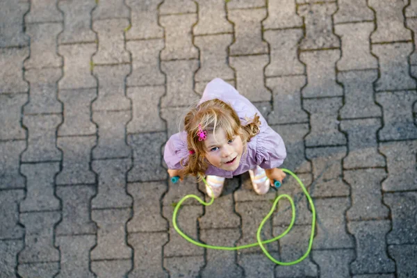 Pequeña niña preescolar saltar y entrenar con saltar la cuerda. Vista desde arriba en lindo niño activo feliz. Deportes de verano y actividad física y mental de los niños. — Foto de Stock