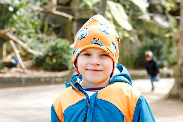 Tavasszal vagy ősszel színes ruhák, kisfiú gyerek szabadtéri portréja. Boldog fiú birtoklás móka egy állatkertben. Mosolygó gyermek — Stock Fotó