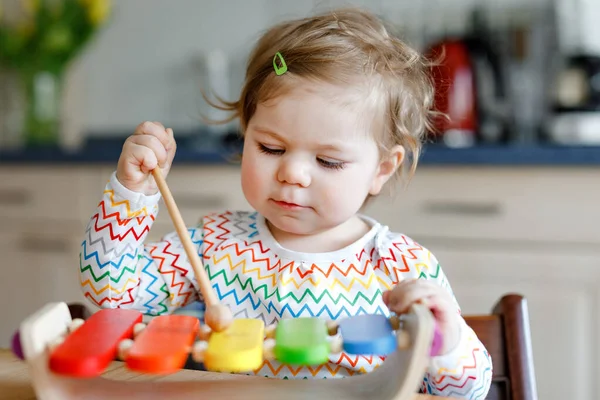 Adorable cute beautiful little baby girl playing with educational wooden music toy at home. Happy excited toddler child learn to play colorful rainbow xylophon. Early education, activity for children. — Stock Photo, Image