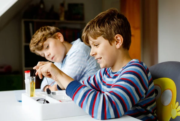 Két srác elektromos fizikai kísérleteket végez házi feladatként otthon. A gyerekek elektromosságot tanulnak. Oktatás. Legjobb barátok, testvérek fizikát tanulnak. — Stock Fotó