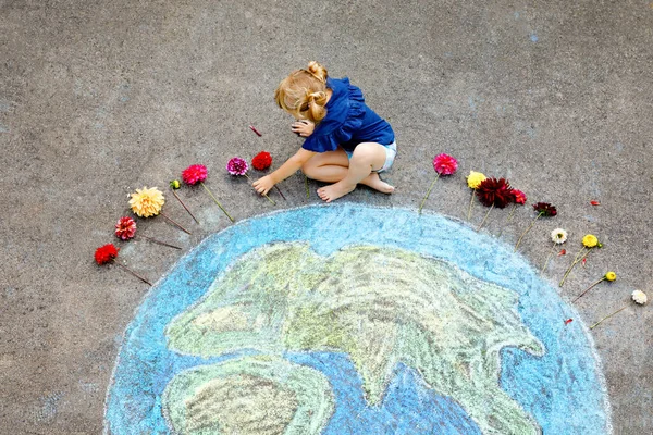 Niña preescolar con flores y tierra globo pintura con tiza de colores en el suelo. Un niño pequeño positivo. Feliz concepto del día de paz. Creación de niños para salvar el mundo, el medio ambiente — Foto de Stock