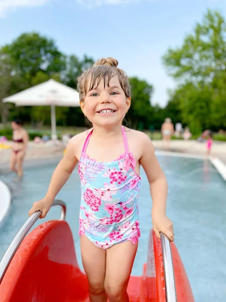 Niña preescolar salpicando en una piscina al aire libre en el cálido día de verano. Feliz niño sano disfrutando de un clima soleado en la piscina pública de la ciudad. Actividad infantil al aire libre con agua. — Foto de Stock