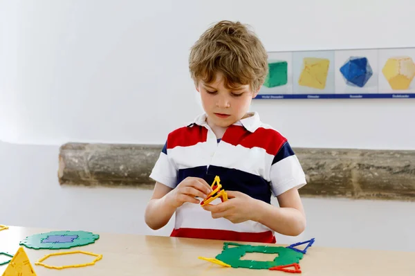 Menino feliz se divertindo com a construção e criação de figuras geométricas, aprendendo matemática e geometria — Fotografia de Stock