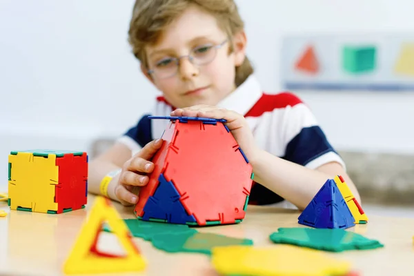 Glücklicher Junge mit Brille, der Spaß am Bauen und Erstellen geometrischer Figuren hat, Mathematik und Geometrie lernt — Stockfoto