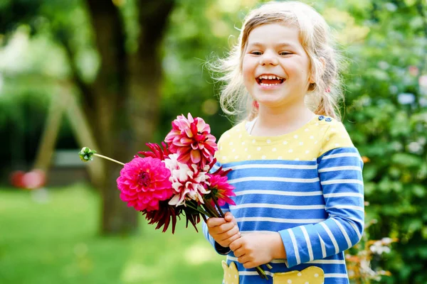 Little preschool girl with huge bouquet of blossoming red and pink dahlia flowers. Happy child holding in hands flowers. Preschooler with peonies for mother or birthday. Gardening children. — Stockfoto