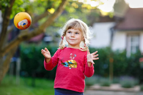귀여운 아기가 밖에서 공을 가지고 노는 모습. 웃는 아이가 잡고 던지고, 웃고, 운동을 하는 것은 행복 합니다. 자녀들과 함께 하는 활동적 인 여가 활동. — 스톡 사진