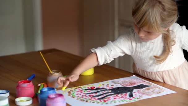 Holka ze školky kreslí na strom listí. Nápady na kreslení prstovými barvami. Malování prstů pro děti. Malování dítěte malováním prstem ručně barvy. Koncept vývoje dětí. Videoklip