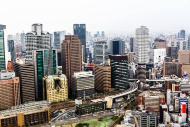 OSAKA, JAPONYA - 18 Mayıs 2015: Japonya 'daki Osaka şatosunun tepesinden gökdelenler, otobanlar ve parklarla Osaka şehrinin ufuk çizgisine bakın. Osaka ilinin başkentidir..
