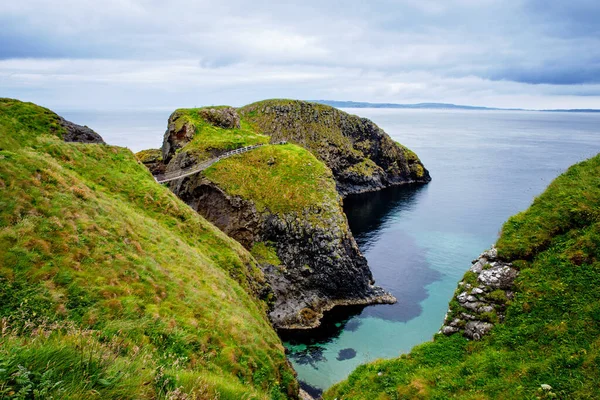 View from Carrick-a-Rede Rope Bridge, famous rope bridge near Ballintoy in County Antrim, Northern Ireland on Irish coastline. Tourist attraction, bridge to small island on cloudy day. — Stock Photo, Image