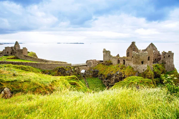 Dunluce Şatosu 'nun kalıntıları, Antrim, Kuzey İrlanda, güneşli bir günde yarı bulutlu gökyüzü. Vahşi Atlantik Yolu yakınlarındaki eski İrlanda kalesi.