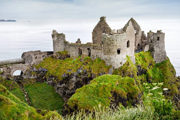 Dunluce Şatosu 'nun kalıntıları, Antrim, Kuzey İrlanda, güneşli bir günde yarı bulutlu gökyüzü. Vahşi Atlantik Yolu yakınlarındaki eski İrlanda kalesi.