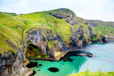 Carrick-a-Rede Köprüsü kıyısında, İrlanda kıyı şeridi üzerinde Kuzey İrlanda 'nın Antrim ilçesi Ballintoy yakınlarında meşhur ip köprüsü. Bulutlu bir günde Vahşi Atlantik Yolu.