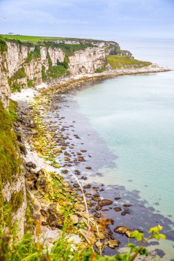 Carrick-a-Rede Köprüsü kıyısında, İrlanda kıyı şeridi üzerinde Kuzey İrlanda 'nın Antrim ilçesi Ballintoy yakınlarında meşhur ip köprüsü. Bulutlu bir günde Vahşi Atlantik Yolu.