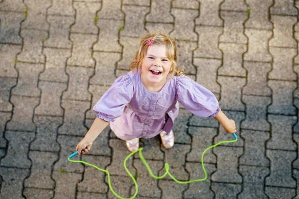 Mała przedszkolanka skacze i trenuje ze skakanką. Widok z góry na słodkie szczęśliwe aktywne dziecko. Sporty letnie i aktywność fizyczna i psychiczna dzieci. — Zdjęcie stockowe