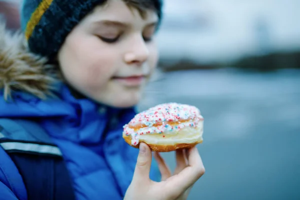 ドイツ語またはrugelach sufganiyotでクレッペルと呼ばれる甘いパイを食べる子供の男の子。ケーキ付きの子供、カーニバルのための宗教的な食べ物ドイツやユダヤのチャヌッカ祭りで断食 — ストック写真