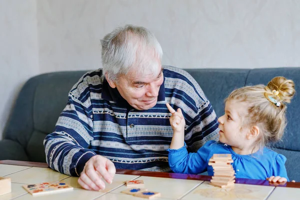 Bella bambina e nonno giocare insieme immagini gioco di carte da tavolo di memoria a casa. Bambino carino e l'uomo anziano divertirsi insieme. Famiglia felice al chiuso — Foto Stock