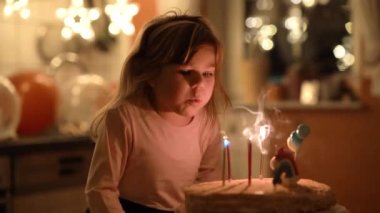 Sevimli küçük kız beşinci doğum gününü kutluyor. Ev yapımı prenses pastası olan şirin bir bebek. Mutlu sağlıklı bebek pastaya 5 mum üflüyor.