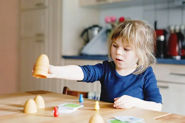 Adorable linda niña jugando juego de salón. Feliz niño sano entrenando la memoria, pensando. Creativo en interiores ocio y educación de los niños durante la pandemia coronavirus covid enfermedad de cuarentena — Foto de Stock