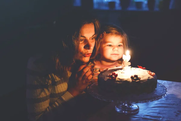 Adorabile bambina che festeggia il suo secondo compleanno. Bambino figlia e giovane madre che soffia candele su torta e candele. Felice sano ritratto di famiglia, mamma amore e felicità — Foto Stock