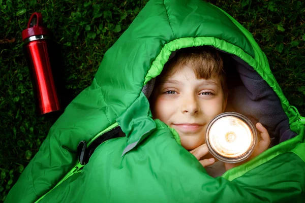 Niño preadolescente de la escuela en el campamento saco de dormir. Actividad al aire libre con niños en verano. Campamento de diversión y aventura, vacaciones en familia y amigos o viaje de fin de semana. Retrato de niño con linterna. —  Fotos de Stock