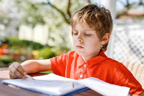 Retrato de menino em casa fazendo trabalhos de casa, escrevendo cartas com canetas coloridas. Criança a fazer exercício, dentro de casa. Escola primária e educação, conceito de escola em casa. — Fotografia de Stock