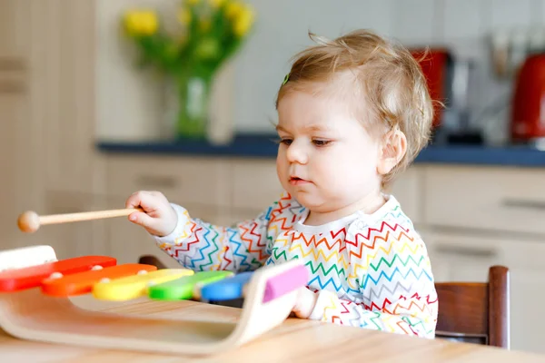 Adorable linda y hermosa niña jugando con un juguete educativo de música de madera en casa. Feliz niño emocionado aprender a jugar colorido xilofón arco iris. Educación temprana, actividad para los niños. — Foto de Stock