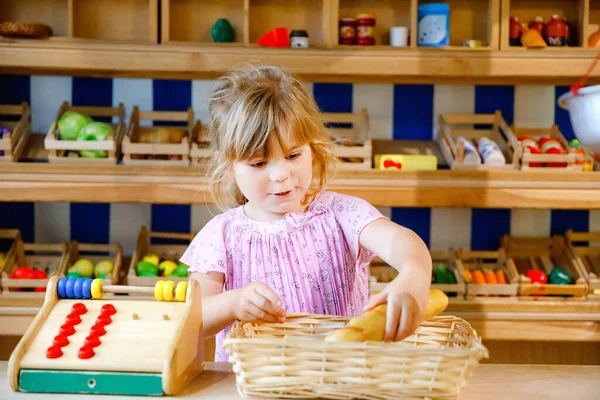 Liten förskola flicka leka med mat och matvaror trä leksaker. Glad aktiv barn spela rollspel som kassör eller säljare, i trä butik eller stormarknad. Utbildning, aktivitet för barn. — Stockfoto