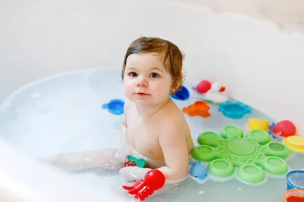 Linda menina adorável tomando banho espumoso na banheira. Criança brincando com brinquedos de borracha de banho. — Fotografia de Stock