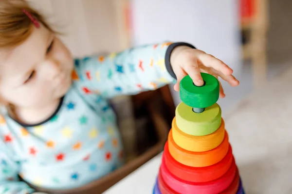 Söt vacker liten flicka leker med pedagogiska leksaker hemma eller på dagis, inomhus. Glad frisk barn har kul med färgglada trä regnbåge leksak pyramid. Grabben lär sig olika färdigheter. — Stockfoto