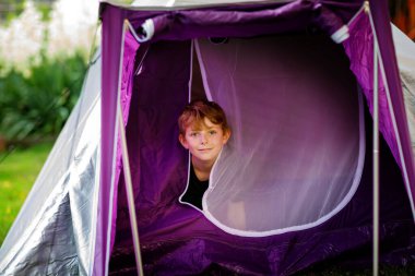 Mutlu çocuk doğa çadırında kamp yapıyor. Yaz aylarında yürüyüş yapan sağlıklı bir okul çocuğu. Çocuksu aile gezisinde ya da okul gezisinde eğleniyor..